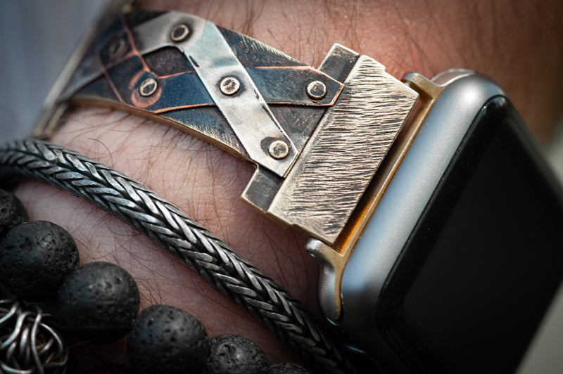 Close-up of the narrow Juggler Apple Watch band on Bruno’s wrist, showcasing the intricate handiwork. The watch band is styled with a silver bracelet.  