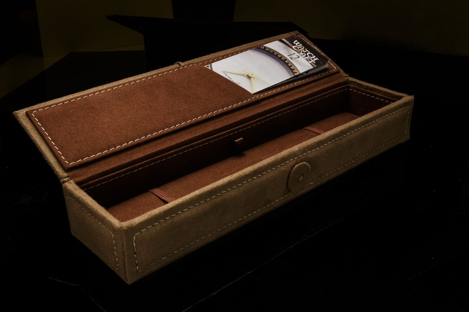 Rich brown suede Watchcraft gift box, open to show artist information and the inside.