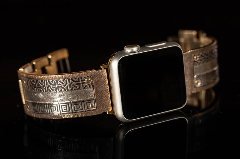 Look at this beauty! Our bestselling Bard Apple watch band, shown here in a wide band. Slices of sterling silver are embossed with Celtic and Greek designs and then riveted by hand onto a solid metal band. Bard sterling silver iWatch facing to the right on a black background.