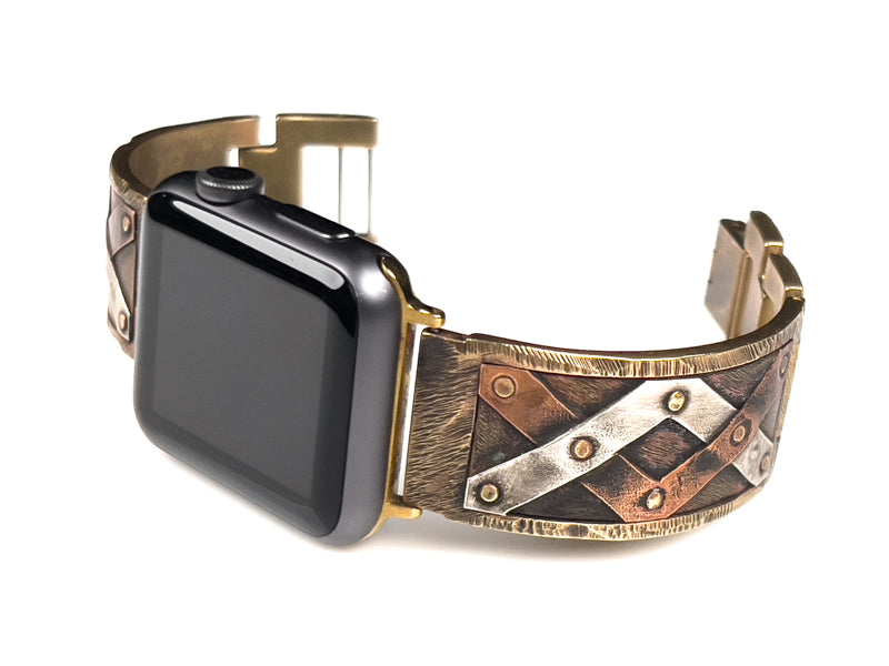 The Juggler Apple Watch band with stripes of copper and silver hand-riveted to the band. Facing left.